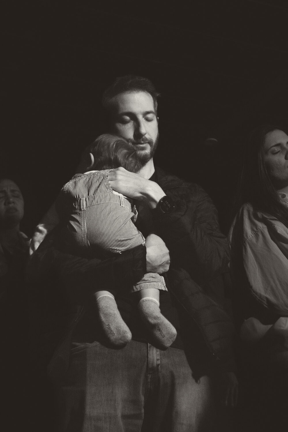 Pai segura o filho pequeno no colo durante o culto
