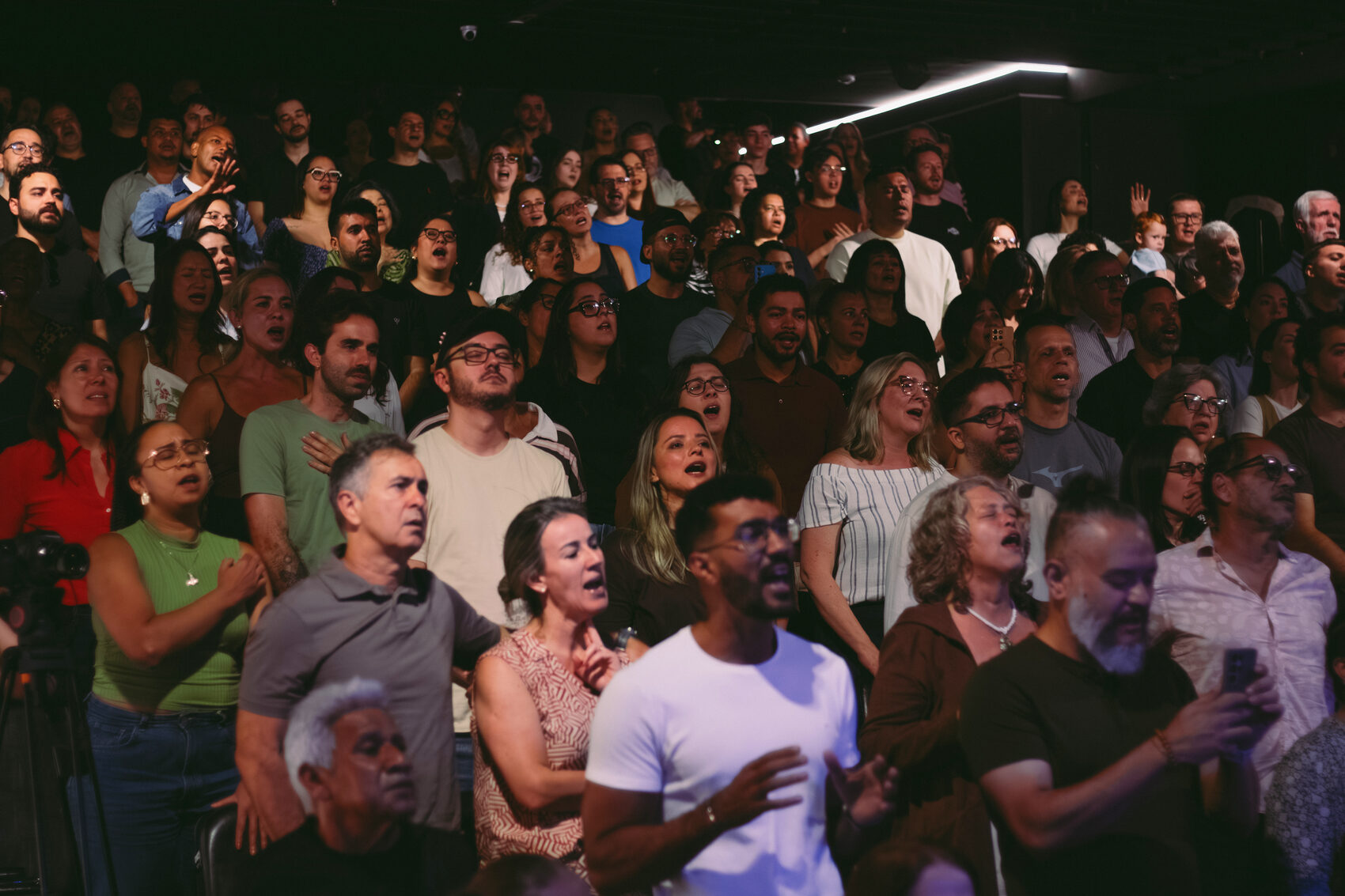 Plateia lotada canta junto, rostos de idades e origens diferentes