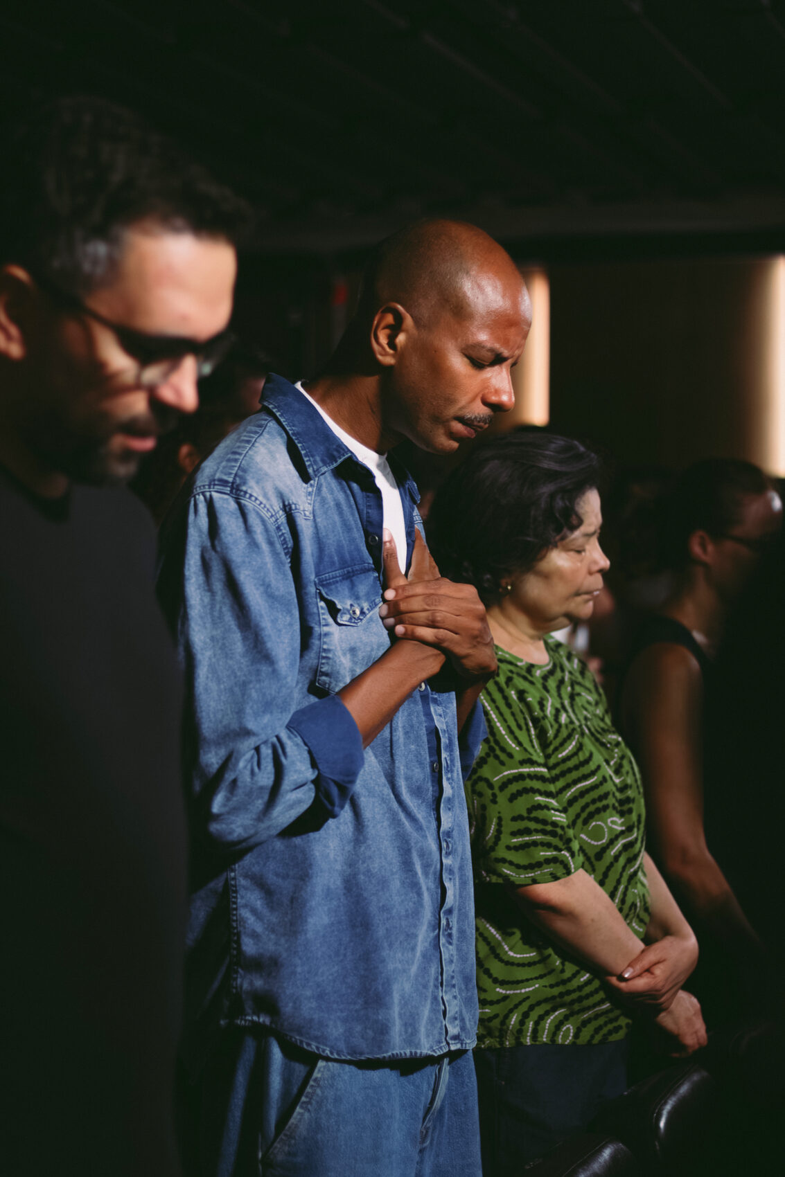 Homem abraça a companheira e a filha durante o culto